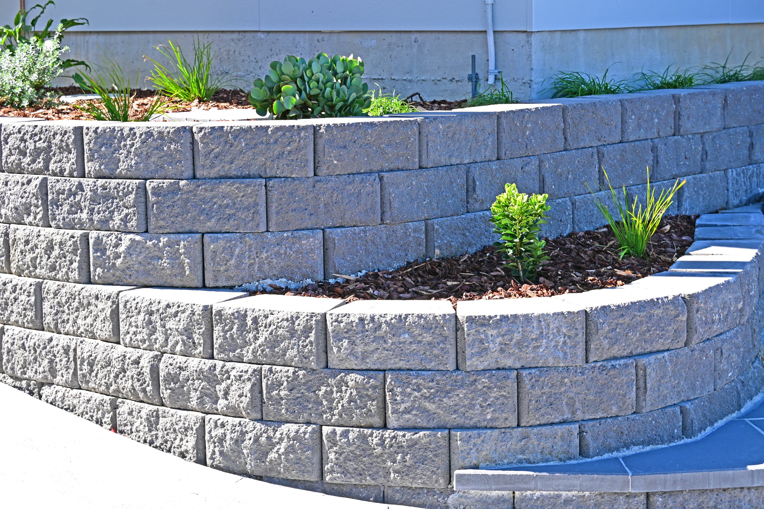 Curved concrete block retaining wall with garden