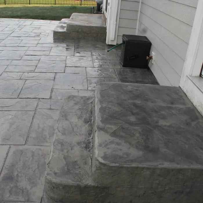 Concrete patio with rectangular pavers and drainage opening