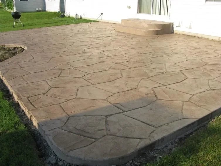 Finished stamped concrete patio with stone pattern in residential backyard